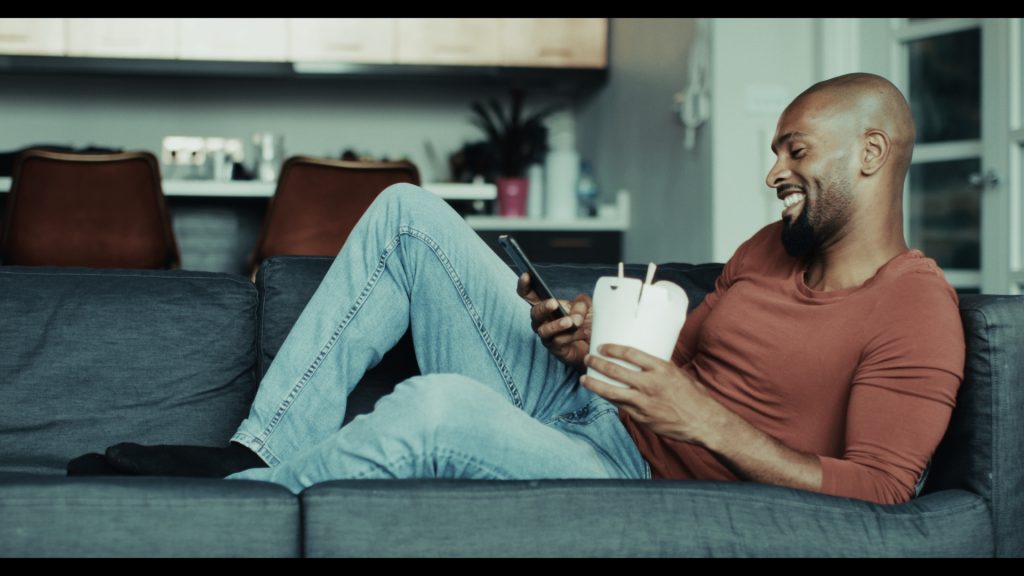Mann auf dem Sofa mit Smartphone und Kaffeebecher – Look Bleach Bypass